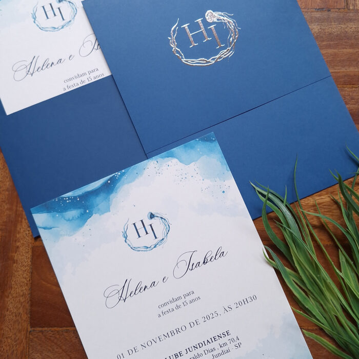 convite de 15 anos com tema de fundo do mar. Envelope em papel Color Plus Toronto, monograma em relevo metálico prata, texto em epóxi azul marinho, impressão digital aquarelada.